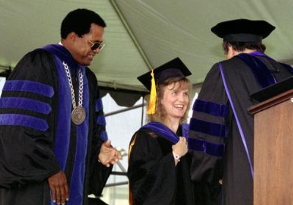 a person in a graduation gown shaking hands with another person in a cap and gown