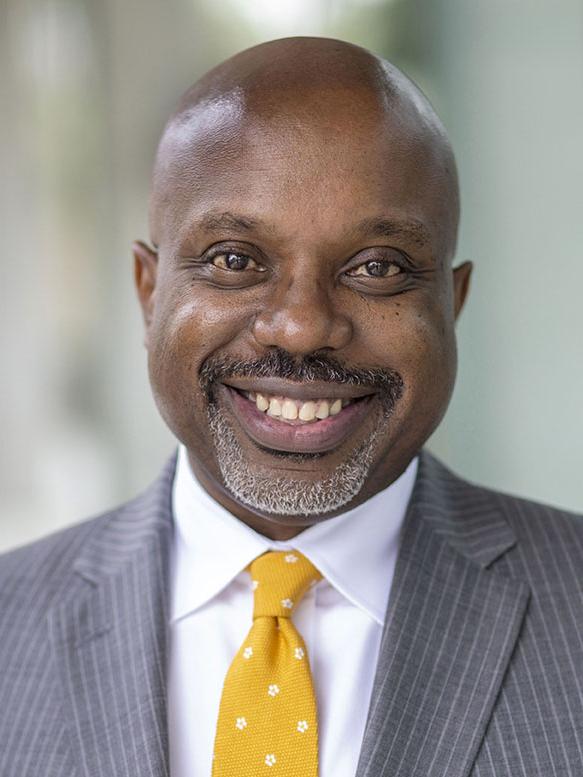 A person wearing a suit and tie smiling.