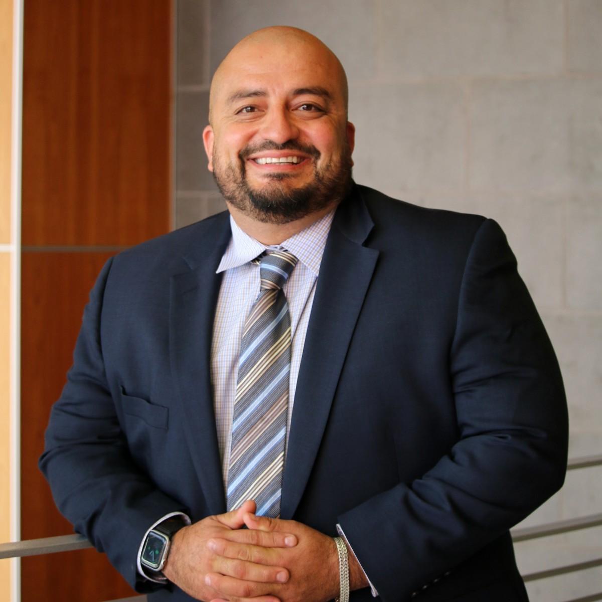 Headshot of Alejandro Macias in a blue suit and tie.