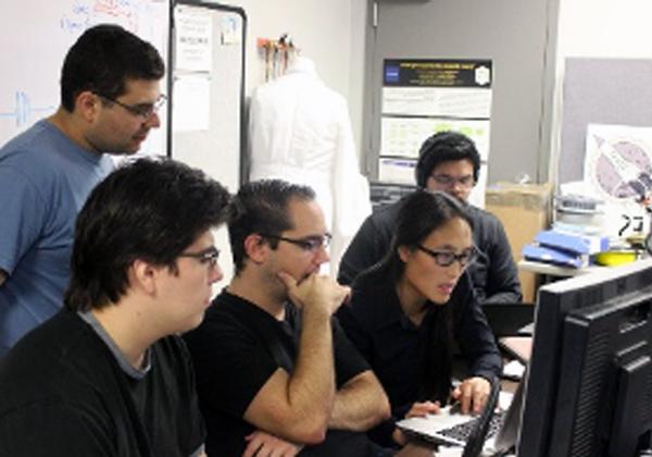 students surround faculty work on computer