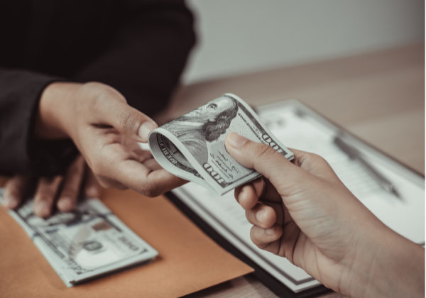 Hands crossing money across desk