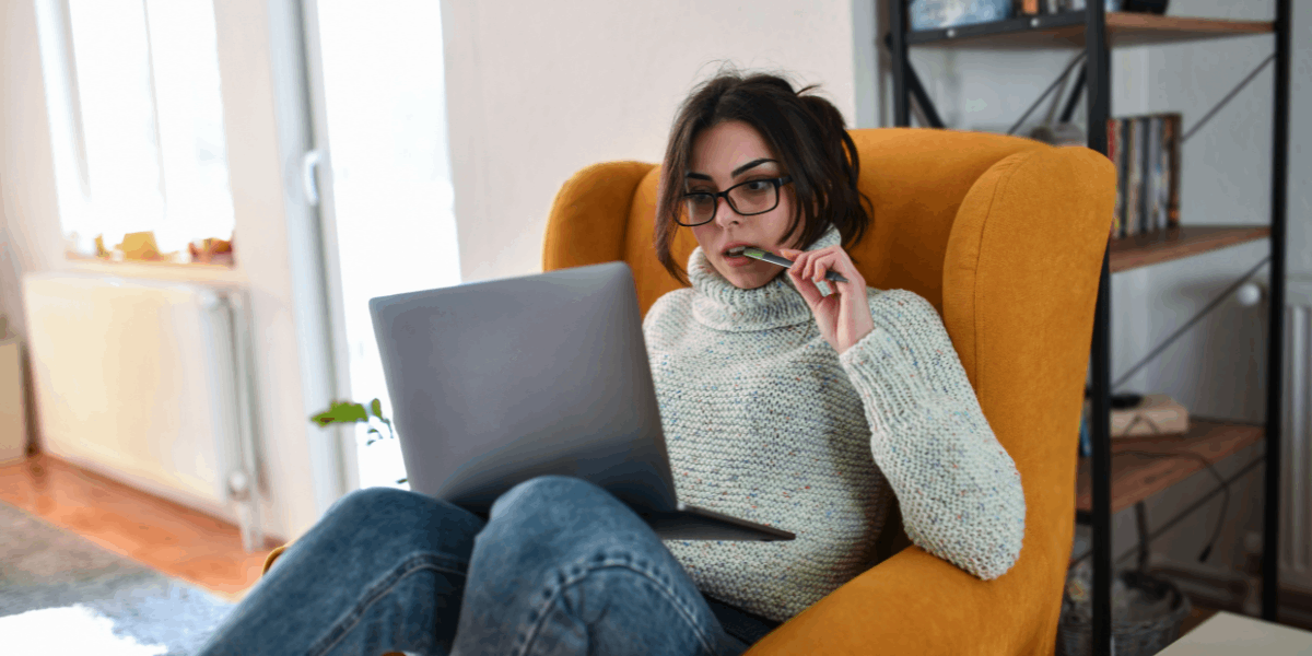 Female student in warm sweater on chair with laptop